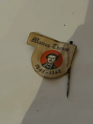 Detaljvisning av papirmerket fra 1948 som viser papirlagene, brettingen og metallnålen.